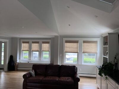 Woven wood shades on a bay window and glass door in a living room in West Roxbury, MA